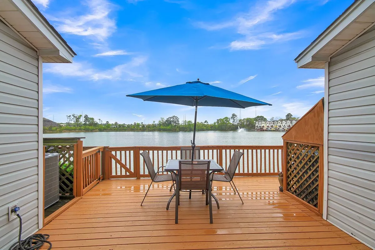 An outdoor dining space on a wooden deck with a table, blue umbrella, and direct lake views, perfectly positioned for morning coffees or sunset toasts.