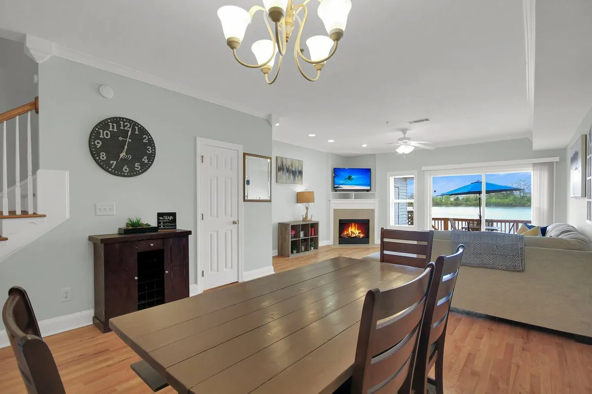 A welcoming dining area with a large table set near a fireplace and a grand window with scenic views. The entertainment center and cozy decor set the stage for both family dinners and festive gatherings.