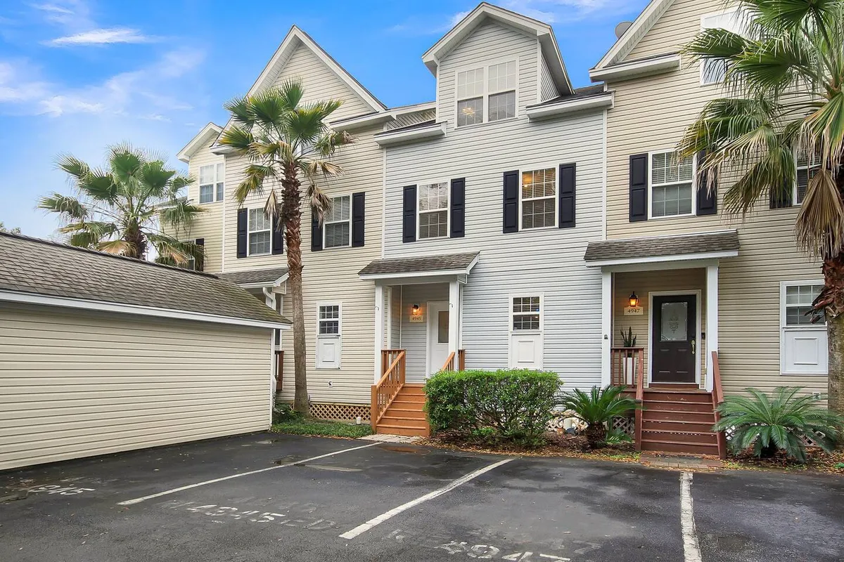 A picturesque front entrance framed by lush palm trees and greenery, with a view of the steps leading up to the home. The scene suggests a welcoming return after a day of adventure, and the ideal spot for quiet moments together.